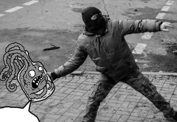 Black and white photo of a hooded individual with an illustration of a creature with tentacles in his hand
